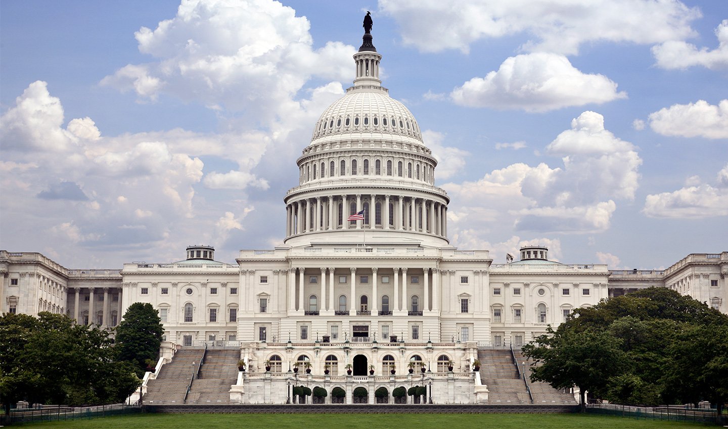 United States Capitol building in front of a cloudy blue sky