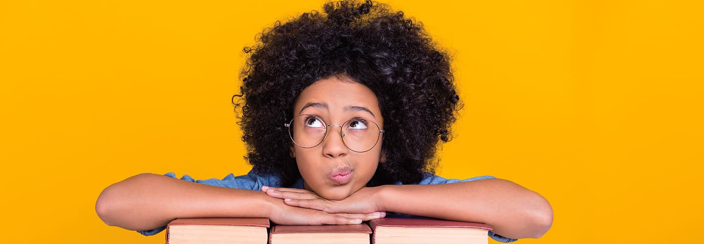 Image of a student wearing glasses and folding arms on pile of books