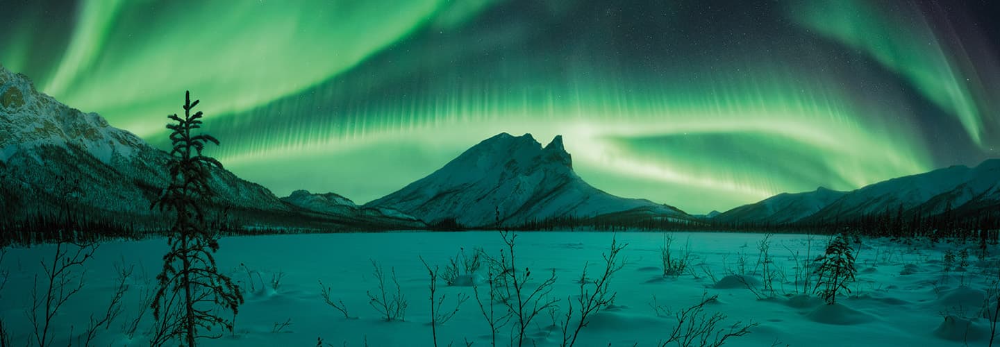 Photo of Northern Lights in a snowy mountain landscape