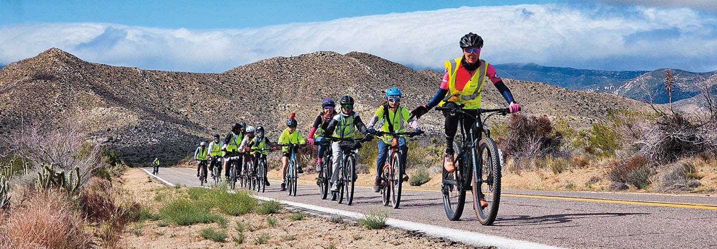 mage of a group of bikers traveling through desert landscape
