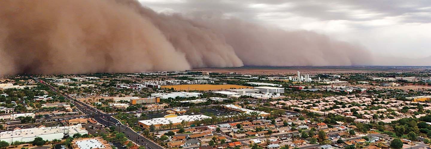 Bird&apos;s eye view of a dust storm passing over a city